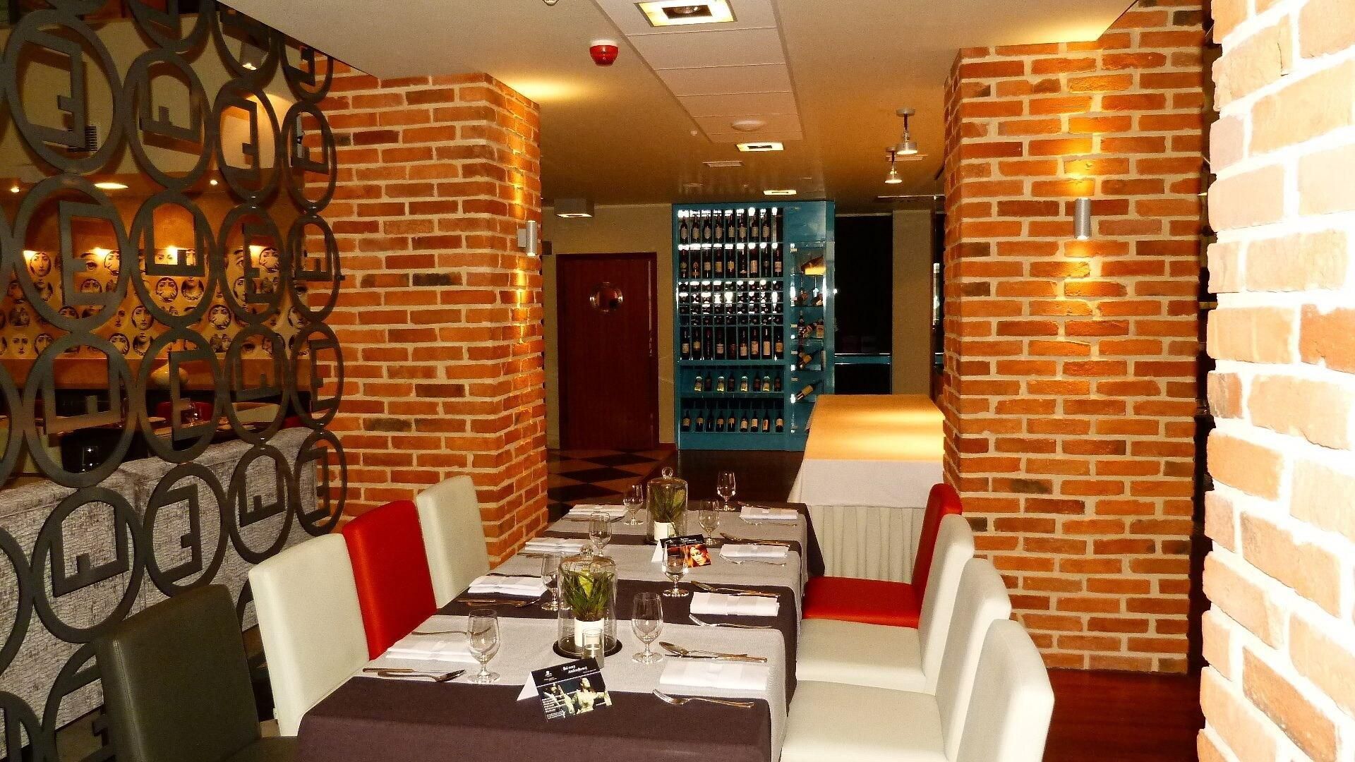 A restaurant interior with brick walls, a bar area, and a dining table set for two.