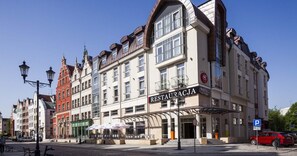 A multi-story building with a restaurant on the ground floor, a hotel on the second floor, and a parking sign in the foreground.