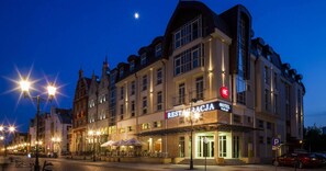 A hotel with a restaurant on the ground floor, featuring a modern facade and illuminated signage.
