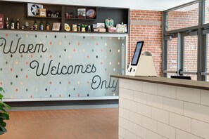 A reception area with a 'Warm Welcomes Only' sign, a display of various items, and a brick wall. - Leavenworth Local Hotel (Leavenworth)