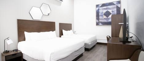 Habitación de hotel con dos camas, un escritorio, una silla y un televisor.