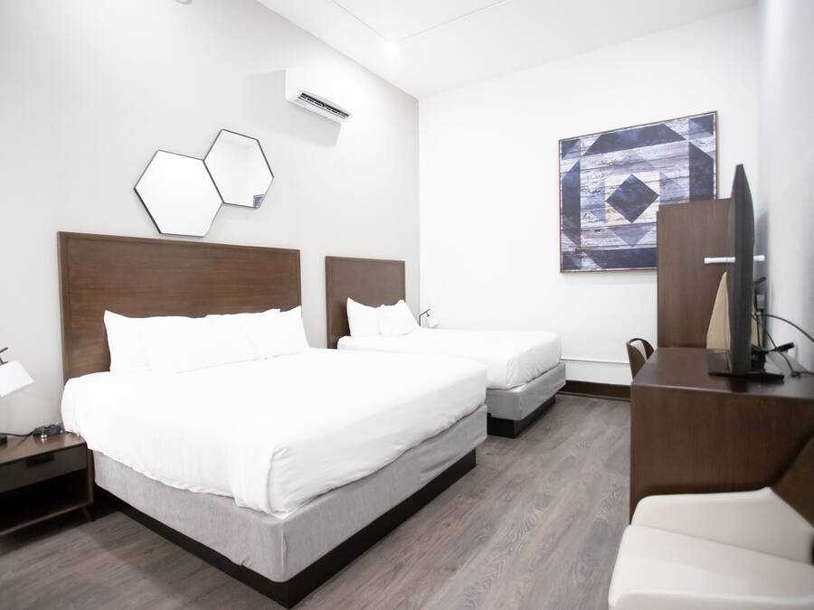 A hotel room with two beds, a desk, a chair, and a TV.