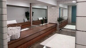 A modern bathroom with a large mirror, a bench, and a sink.