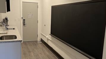 Una cuina moderna amb un gran pantalla negra penjada a la paret, una aixeta integrada i una porta que dona a una altra habitació.