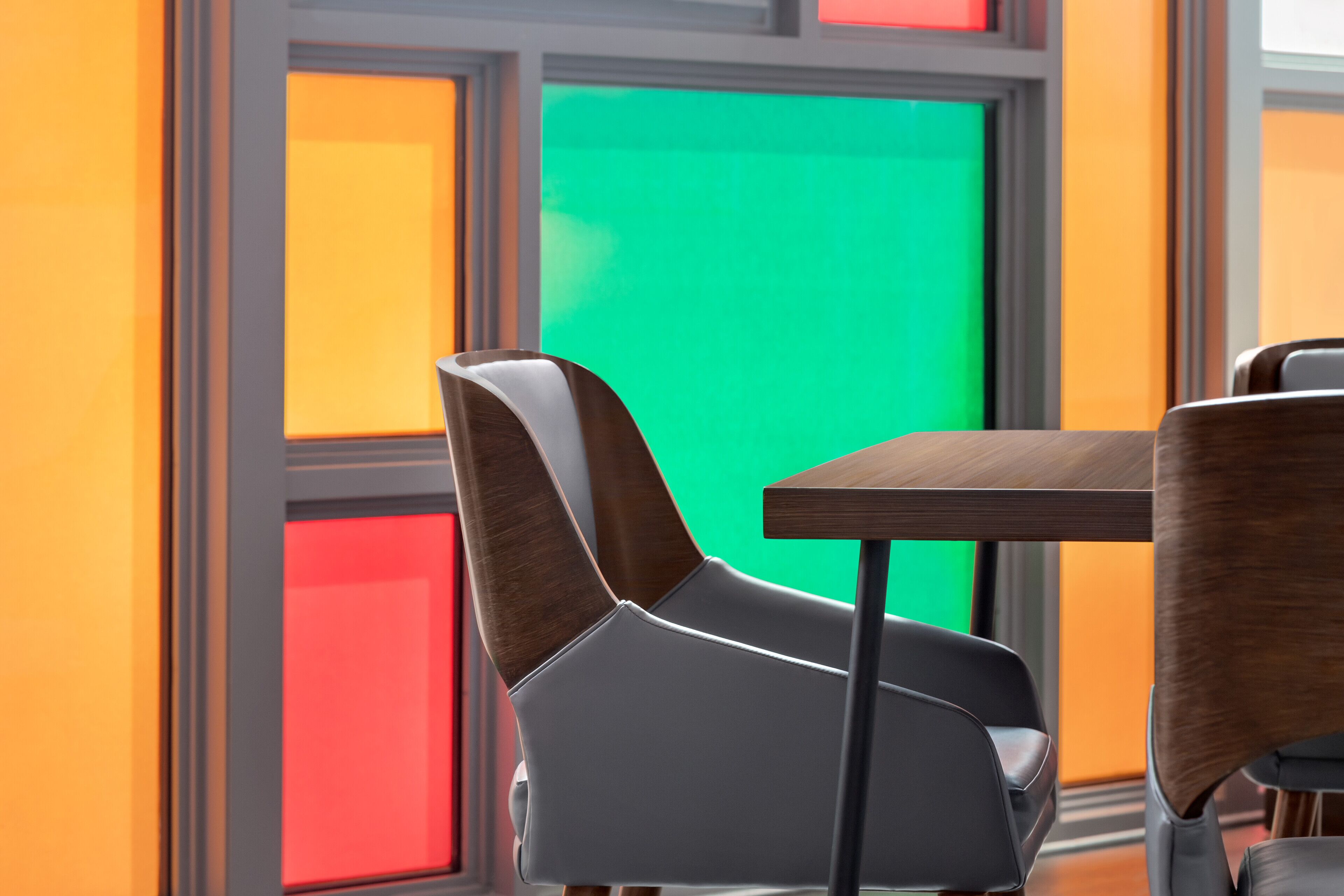 Un interior moderno con una mesa y sillas de madera, una pantalla verde y paneles de pared de colores.