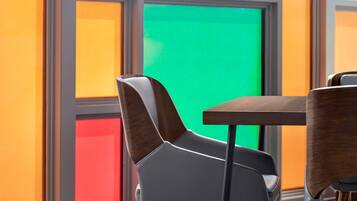 Un interior moderno con una mesa y sillas de madera, una pantalla verde y paneles de pared de colores.