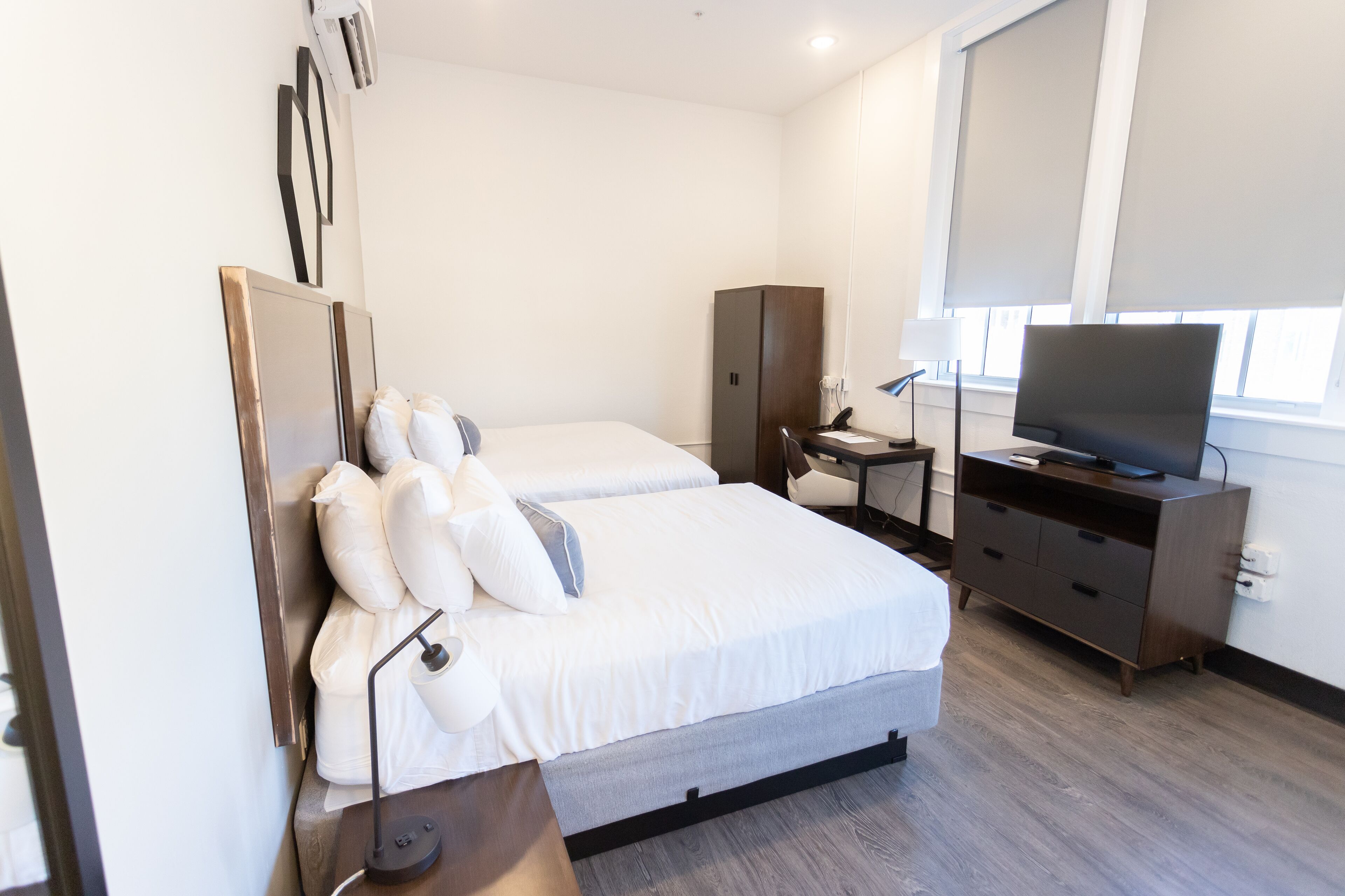 Una camera d'albergo con un letto, una scrivania, una televisione e un armadio.