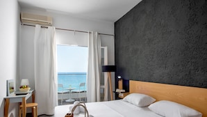 Une chambre d’hôtel avec un lit, un bureau, une chaise, une lampe et une vue sur la mer.