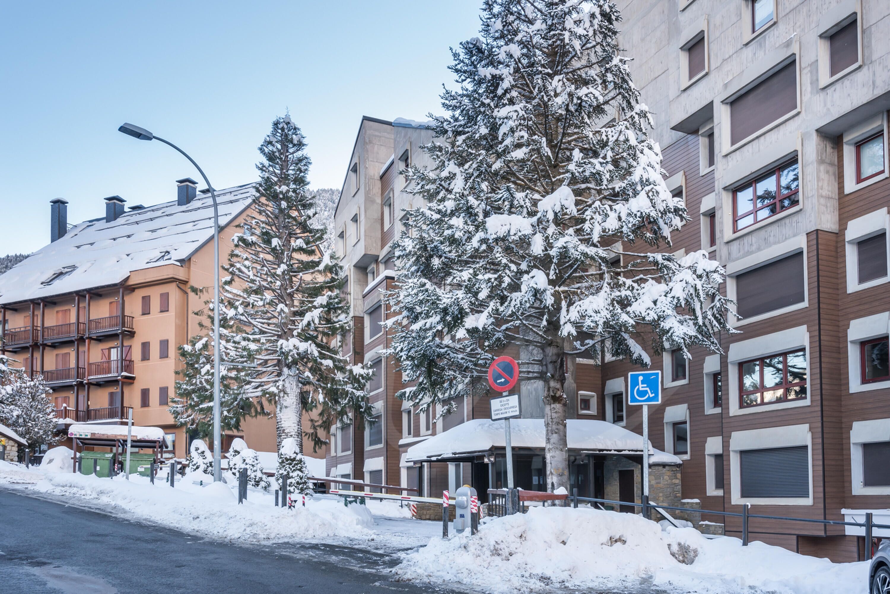 Lumipeitteinen katu, jonka varrella on rakennuksia, mukaan lukien hotelli, jossa on esteettömyysmerkki.