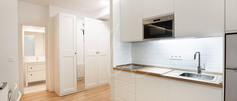 A modern kitchen with white cabinetry, a wooden countertop, and a stainless steel sink.