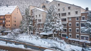 A multi-story building with a snow-covered landscape, a pedestrian walkway, and a sign for a sports rental facility. - Saboredo (Baqueira)