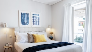 A bedroom with a bed, bedside tables, and artwork on the wall. - Ideal 1 BR Apartment in Petralona (Athens)