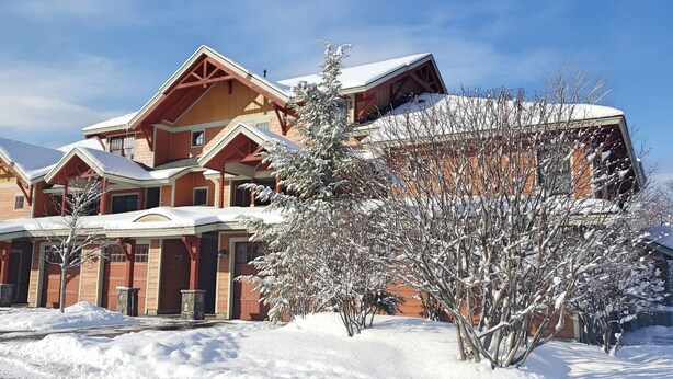 Un grand bâtiment à étages, de style architectural traditionnel, caractérisé par de grandes poutres en bois apparentes et une façade symétrique.