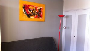 Ein Zimmer mit einem grauen Sofa, einer roten Stehlampe und einer Tür mit weißem Rahmen.