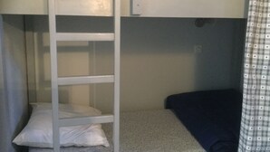 Ein Etagenbett mit einer Leiter, einem Kopfkissen und einer dunkelblauen Decke.