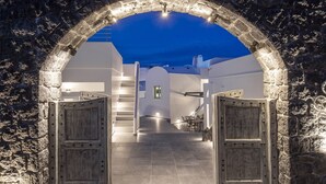 Una entrada de piedra arqueada que conduce a un edificio blanco con una escalera y un comedor.