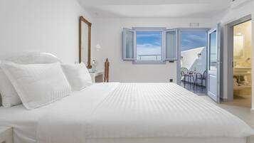 Un dormitorio con una cama grande, un espejo y vistas a un balcón con una mesa y sillas.