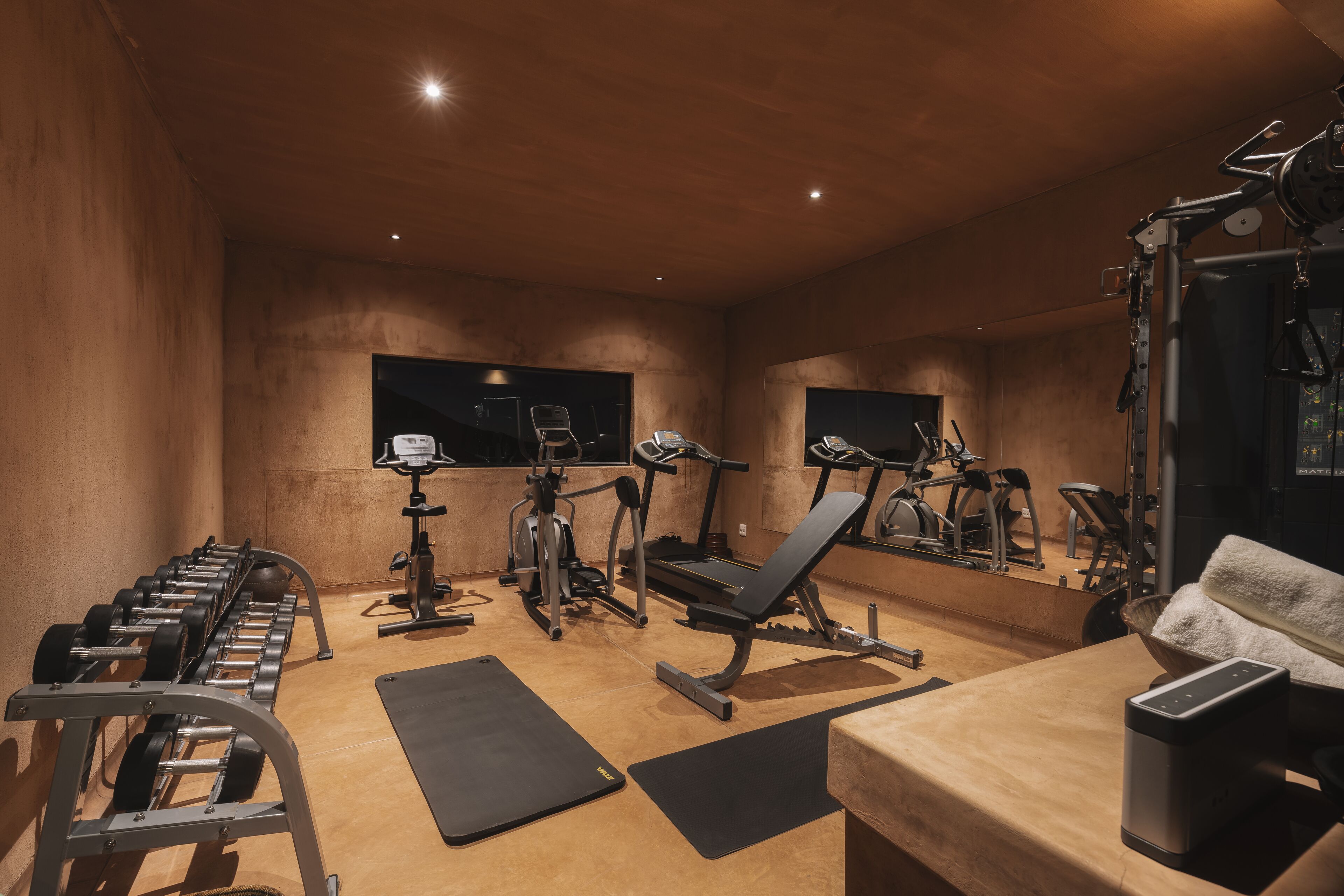 Et fitnessrum med træningsudstyr, en bænk og et spejl.