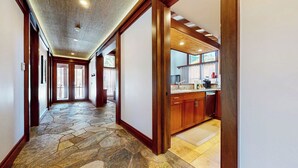 A stone-floored hallway leading to a kitchen with wooden cabinets and a window. - Deluxe 5,000 sq. ft. Home, Hot Tub, Movie Theater, Gas Grill. On Golf Course (Mammoth Lakes)