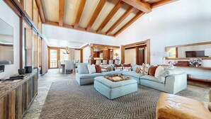 A spacious living room with a large sectional sofa, a herringbone-patterned rug, and a wooden ceiling. - Deluxe 5,000 sq. ft. Home, Hot Tub, Movie Theater, Gas Grill. On Golf Course (Mammoth Lakes)