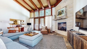 A spacious living room with a large sofa, a fireplace, and a television. - Deluxe 5,000 sq. ft. Home, Hot Tub, Movie Theater, Gas Grill. On Golf Course (Mammoth Lakes)