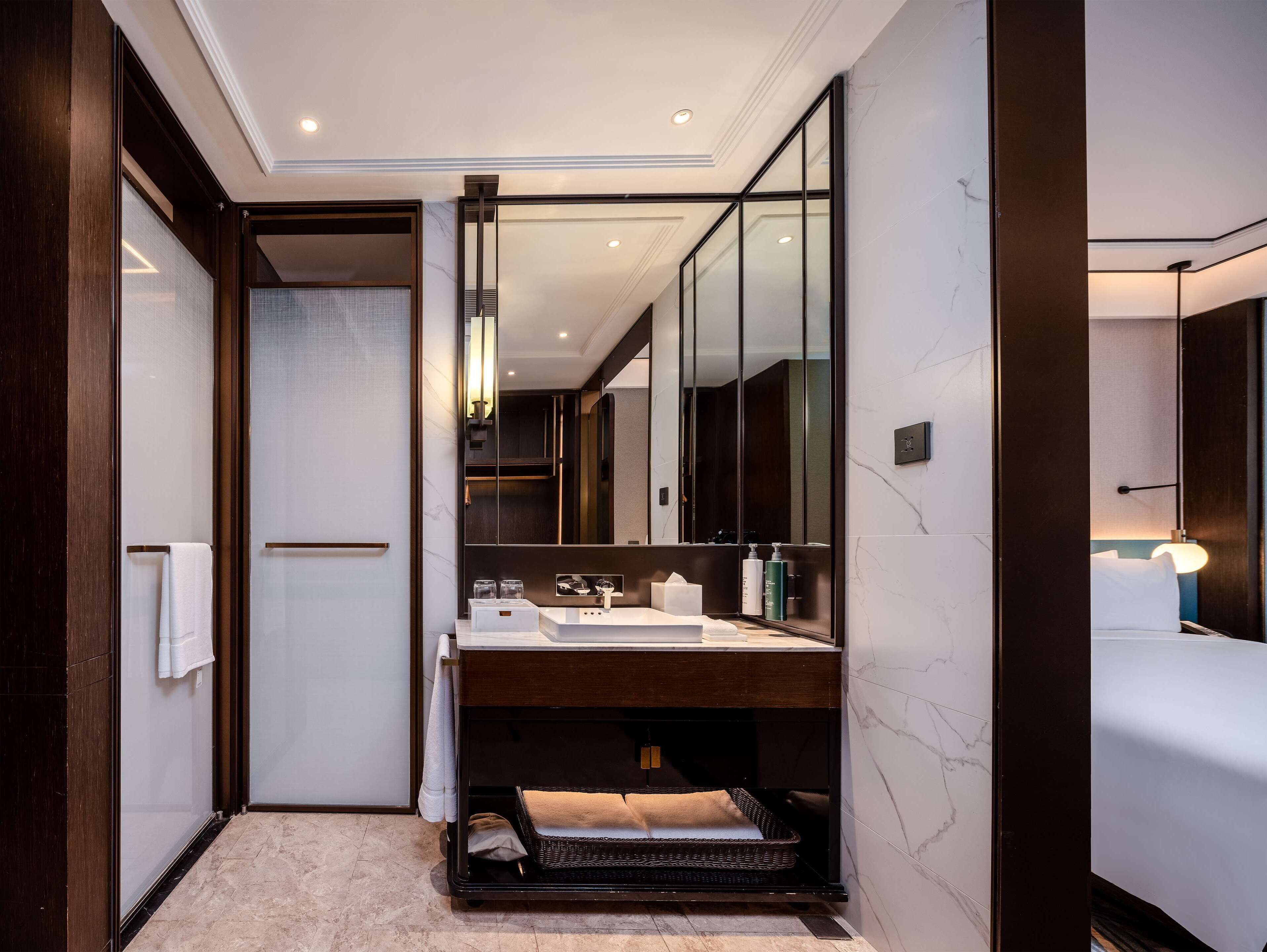 A modern bathroom with a large mirror, a sink, and a bathtub.