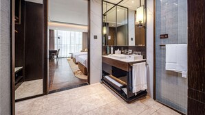 Uma casa de banho de hotel moderna com um espelho grande, uma pia com barra de toalhas e zona de duche.