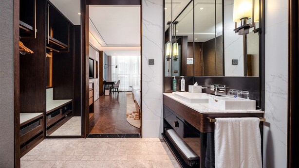 Uma casa de banho moderna com um espelho grande, uma toucador e um closet amplo.