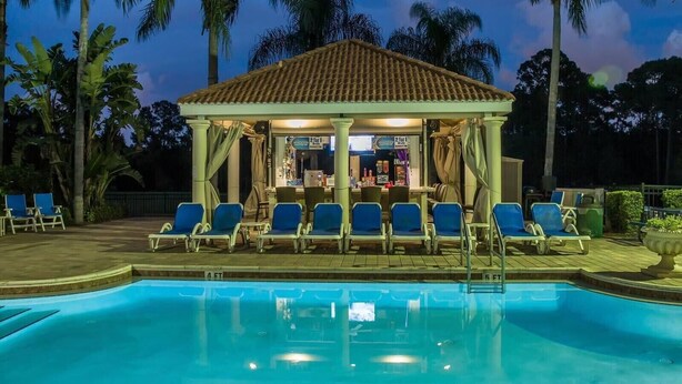 A poolside bar area with a covered seating area, lounge chairs, and a pool. - 7BR Family & Spacious Group Retreat!  Sleeps 14! Private Pool! 15 Min to Disney! (Kissimmee)