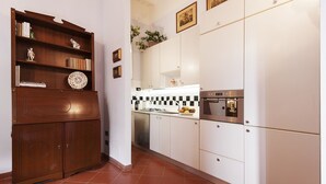A kitchen with white cabinets, a wooden cabinet with decorative items, and a tiled backsplash. - Il Battistero Apt - Luxury Apartments at 20 steps from Duomo; Elevator equipped. (Firenze)