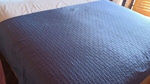 Una cama con almohadas blancas y una colcha azul.