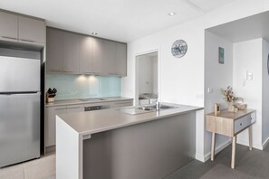 A modern kitchen with a built-in island, stainless steel appliances, and a minimalist design. - Point Grey Apartment 7 (Lorne)