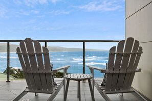 Deux fauteuils Adirondack sont placés face à l’océan, offrant une vue sur les vagues.