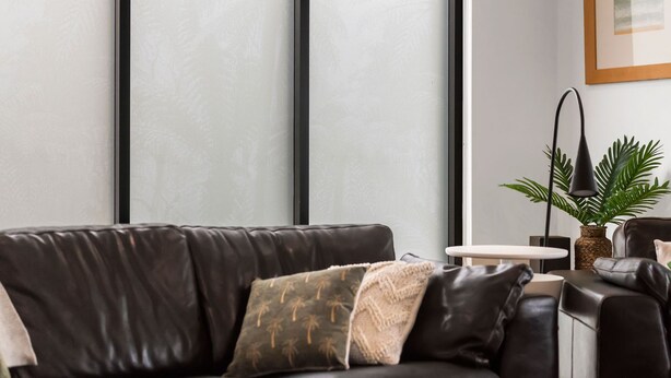 A modern living room with a leather sofa, a small round table, a floor lamp, and a potted plant. - Oceania 3 (Lorne)