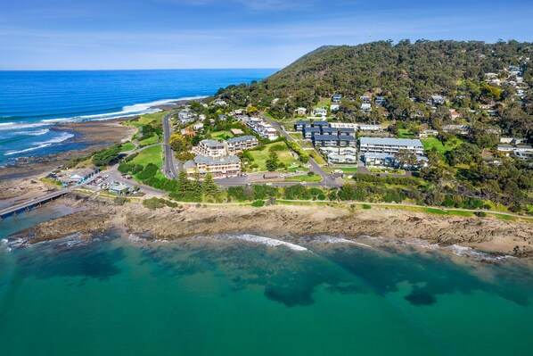 Vista aérea de una zona residencial costera con casas, una playa y un puente.