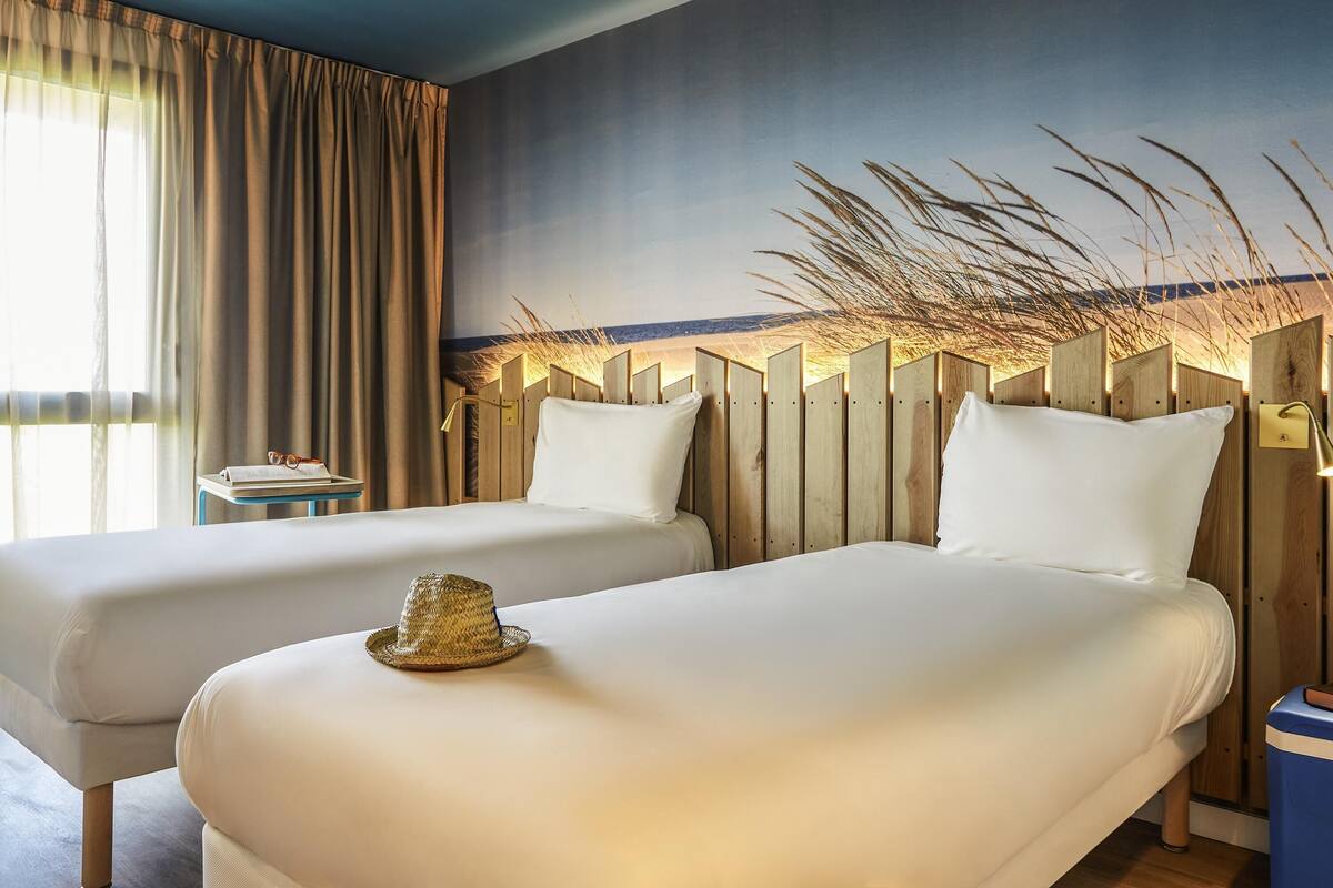 Ein Hotelzimmer mit zwei Betten, einem Nachttisch und Blick auf den Strand.