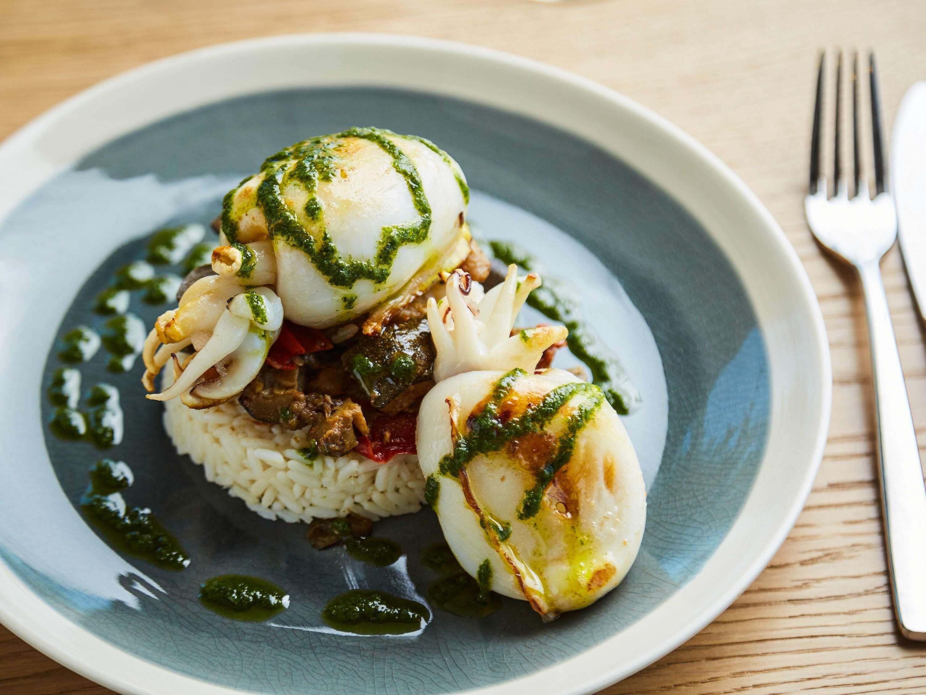 Une assiette contenant des œufs pochés, du riz et des légumes, le tout agrémenté d’une sauce verte.