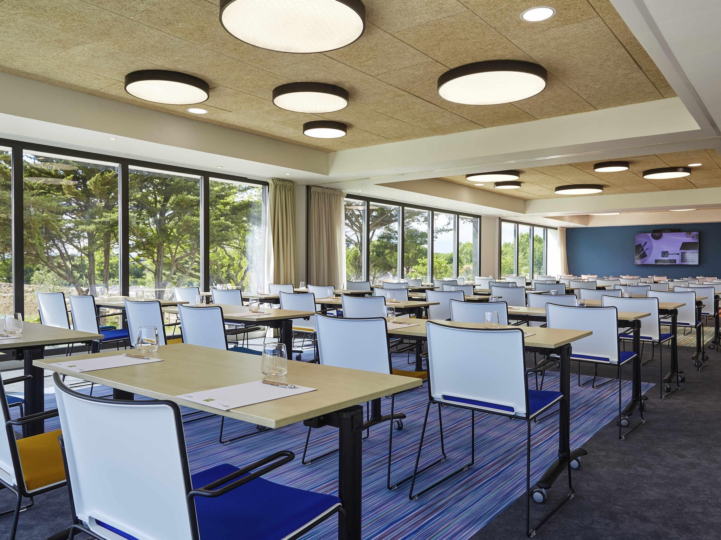 A conference room with tables, chairs, and large windows.