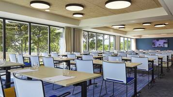 A conference room with tables, chairs, and large windows.