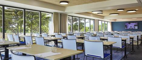 A conference room with tables, chairs, and large windows.