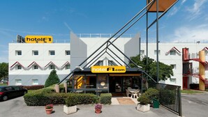 A modern hotel with a prominent yellow sign, a visible entrance, and a staircase leading to the entrance. - hotelF1 Avignon Nord (Sorgues)