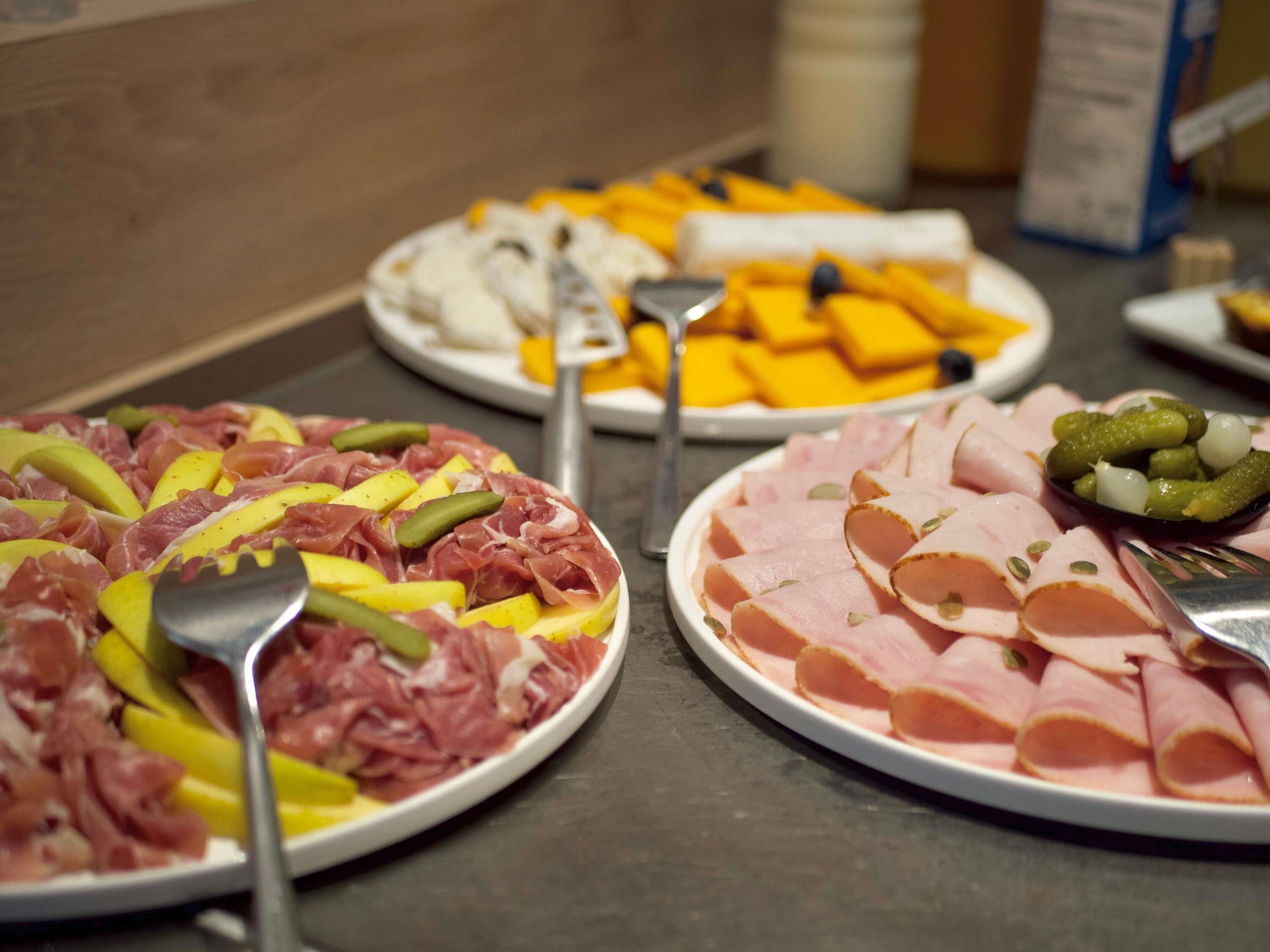 Een buffet met diverse gerechten, waaronder vleeswaren en kazen.