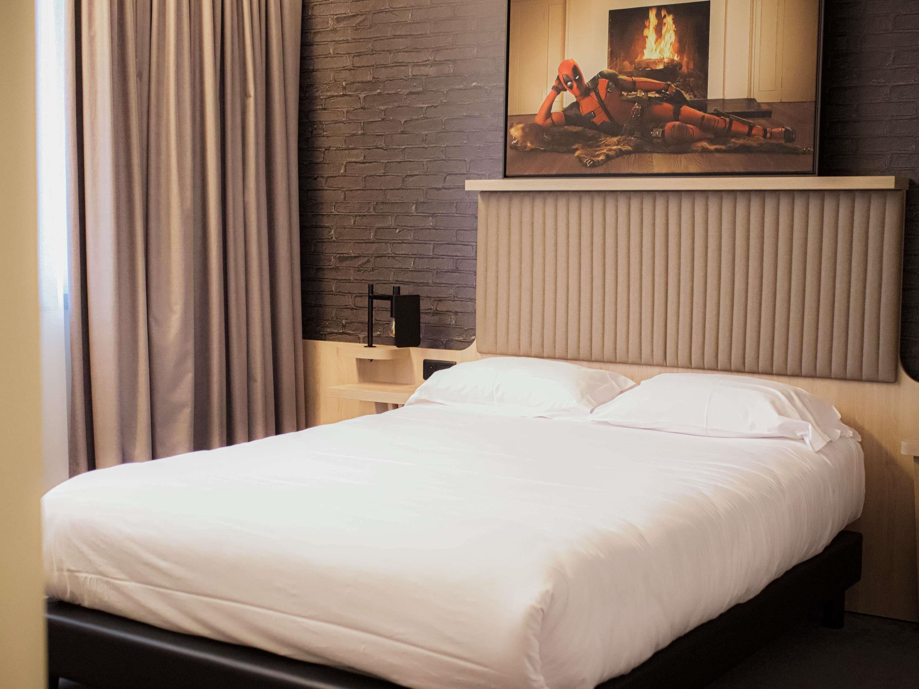 Una cama bien tendida con sábanas blancas en una habitación de hotel moderna.