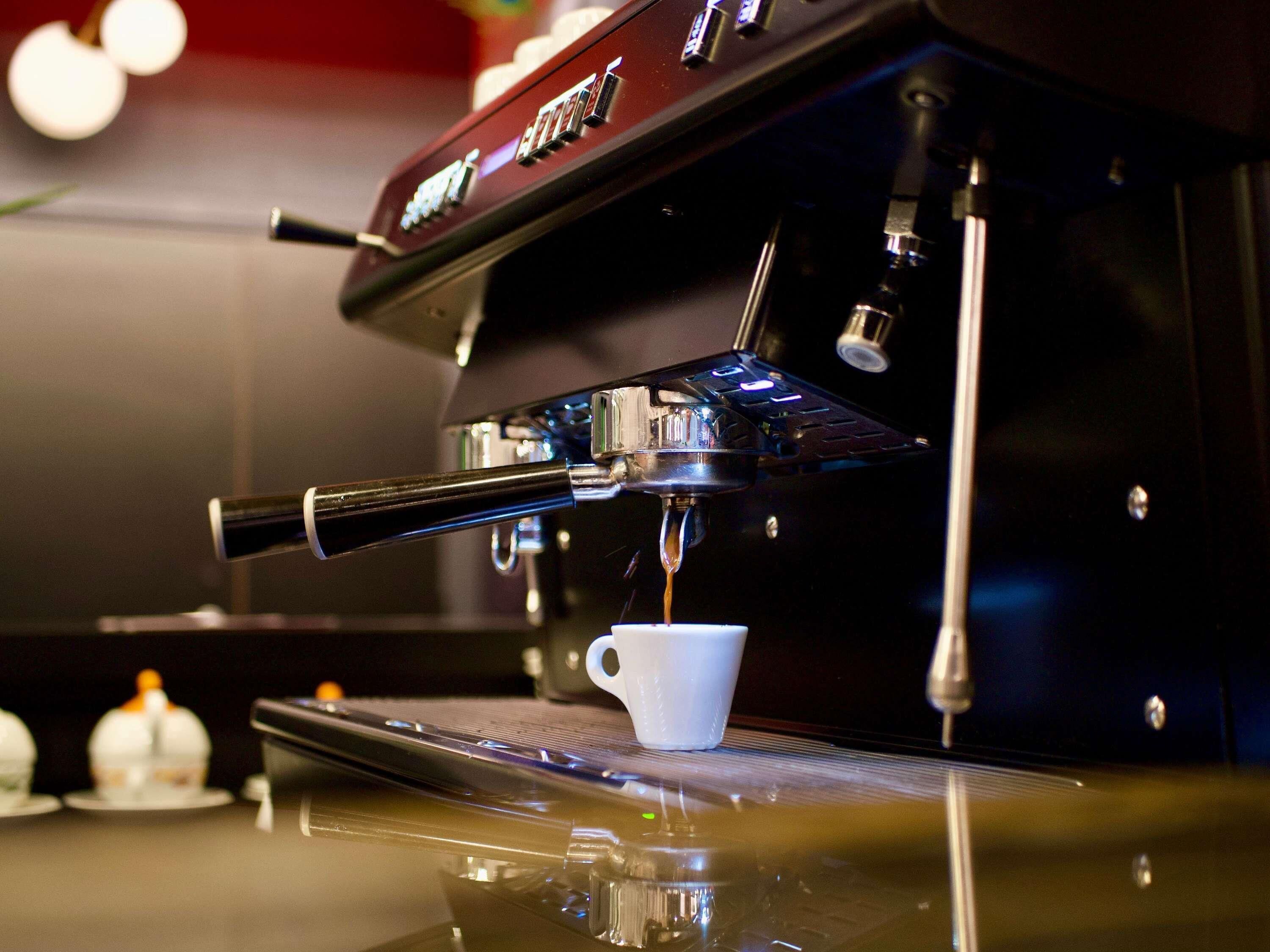 A coffee machine with a cup placed underneath the spout, ready for brewing.