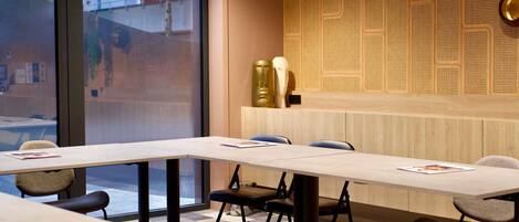 A conference room with a large table, chairs, and a patterned wall.