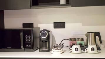 Una cocina con microondas, cafetera y tetera.