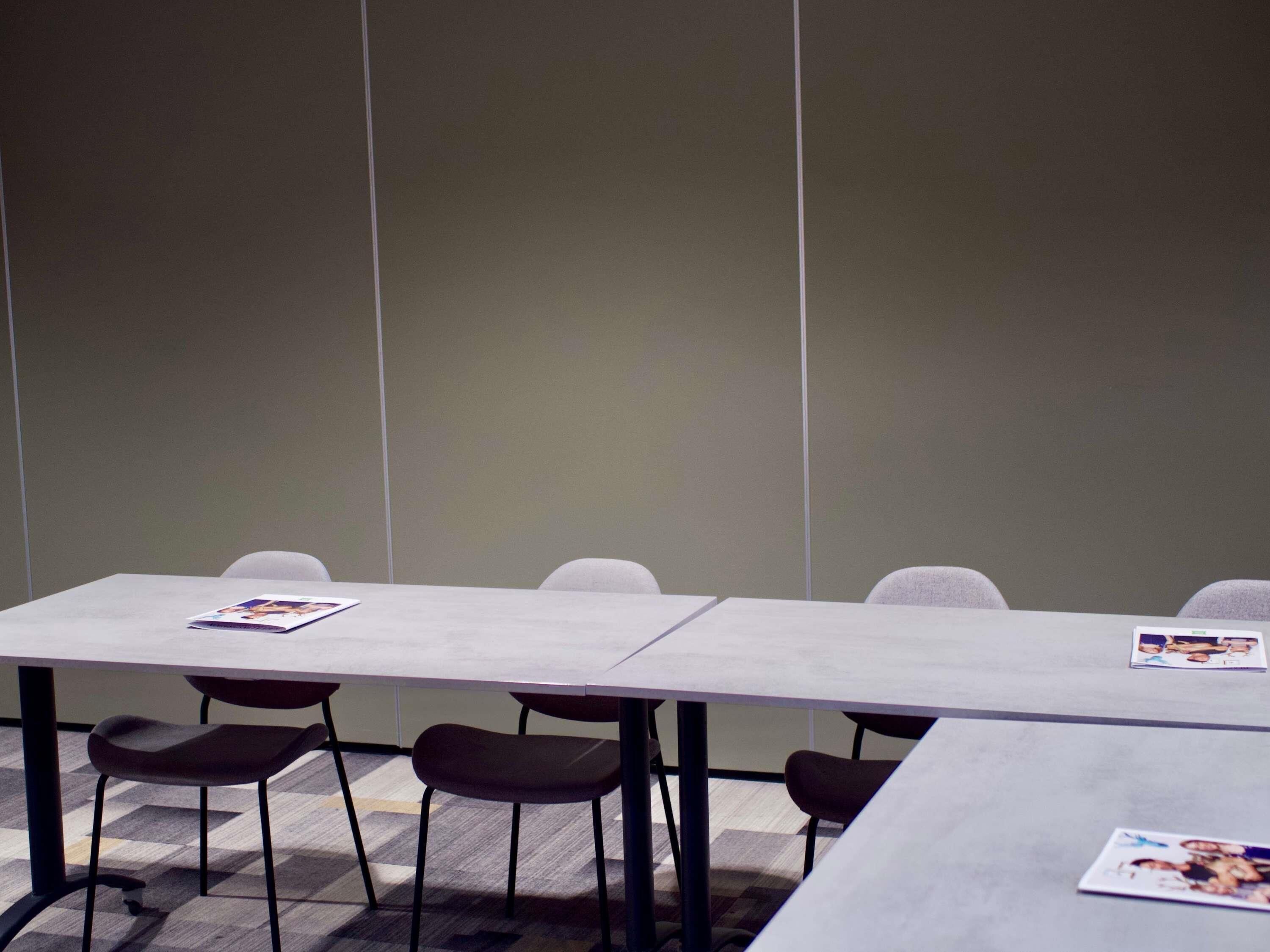 Ein Konferenzraum mit einem langen Tisch, vier Stühlen und zwei Zeitschriften auf dem Tisch.