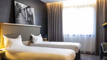 Habitación de hotel con dos camas, un ventanal con cortinas, cabecero y un cuadro en la pared.
