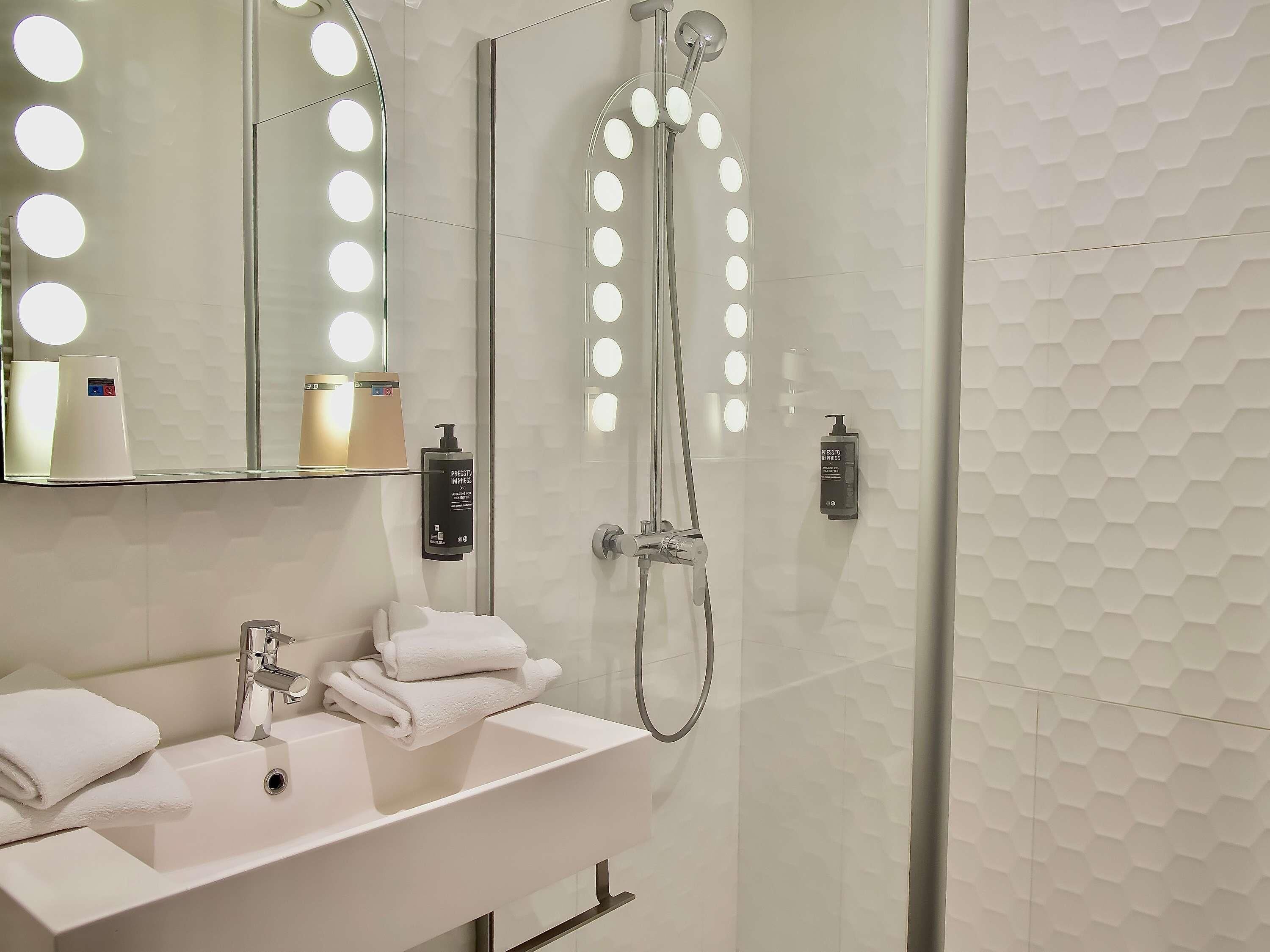A bathroom with a sink, mirror, and shower.