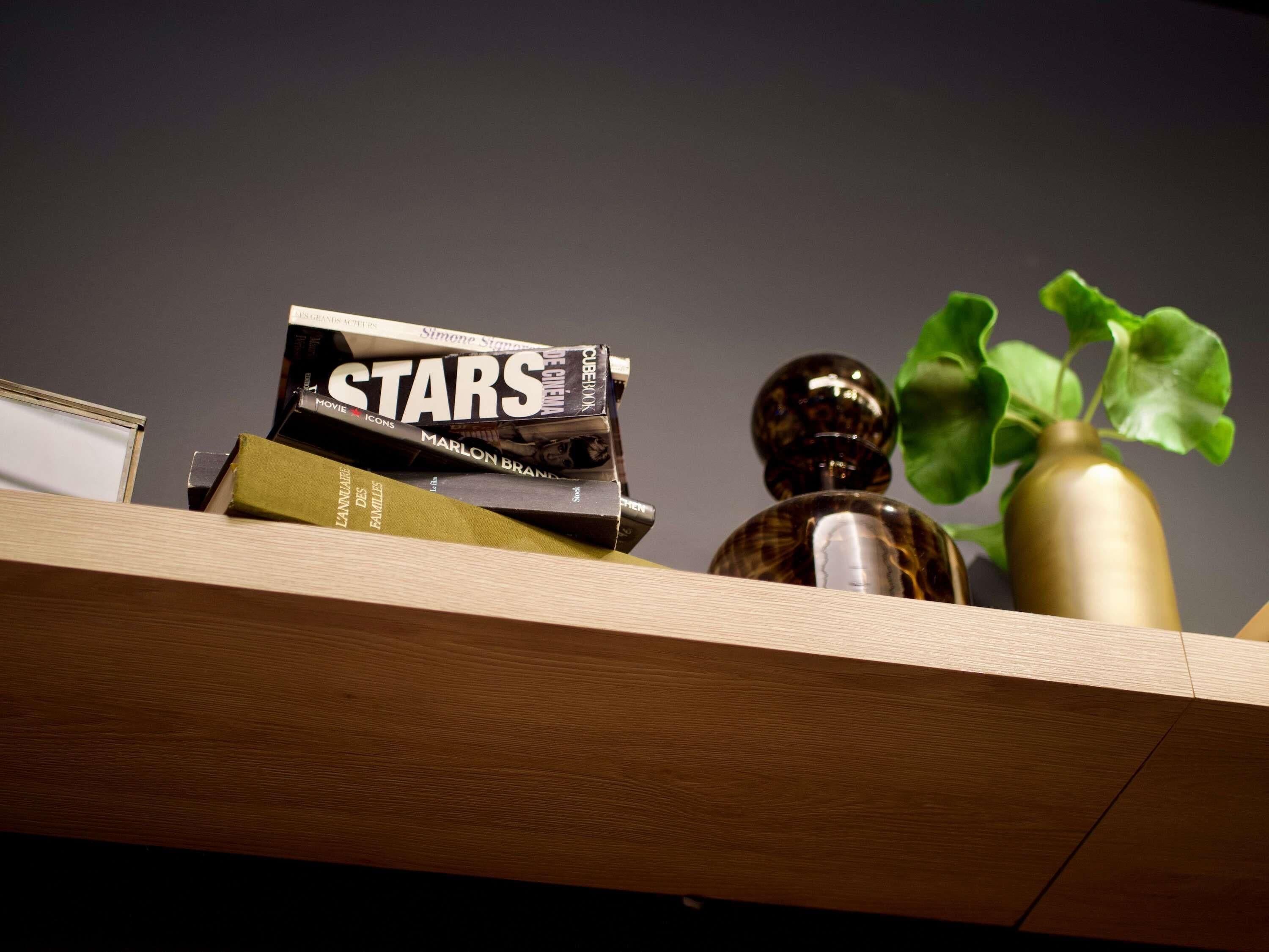 A wooden shelf with books, a decorative bottle, and a green plant.